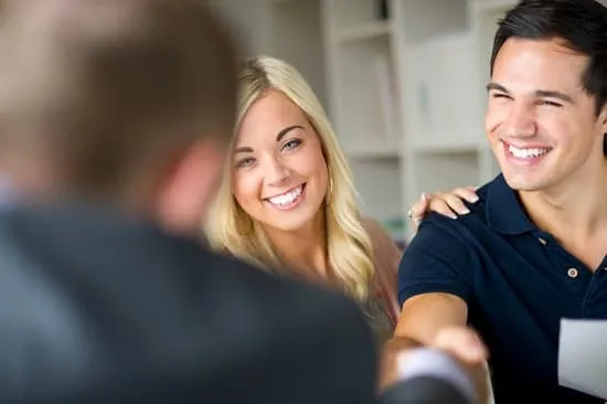 a happy younger couple talking with a businessman